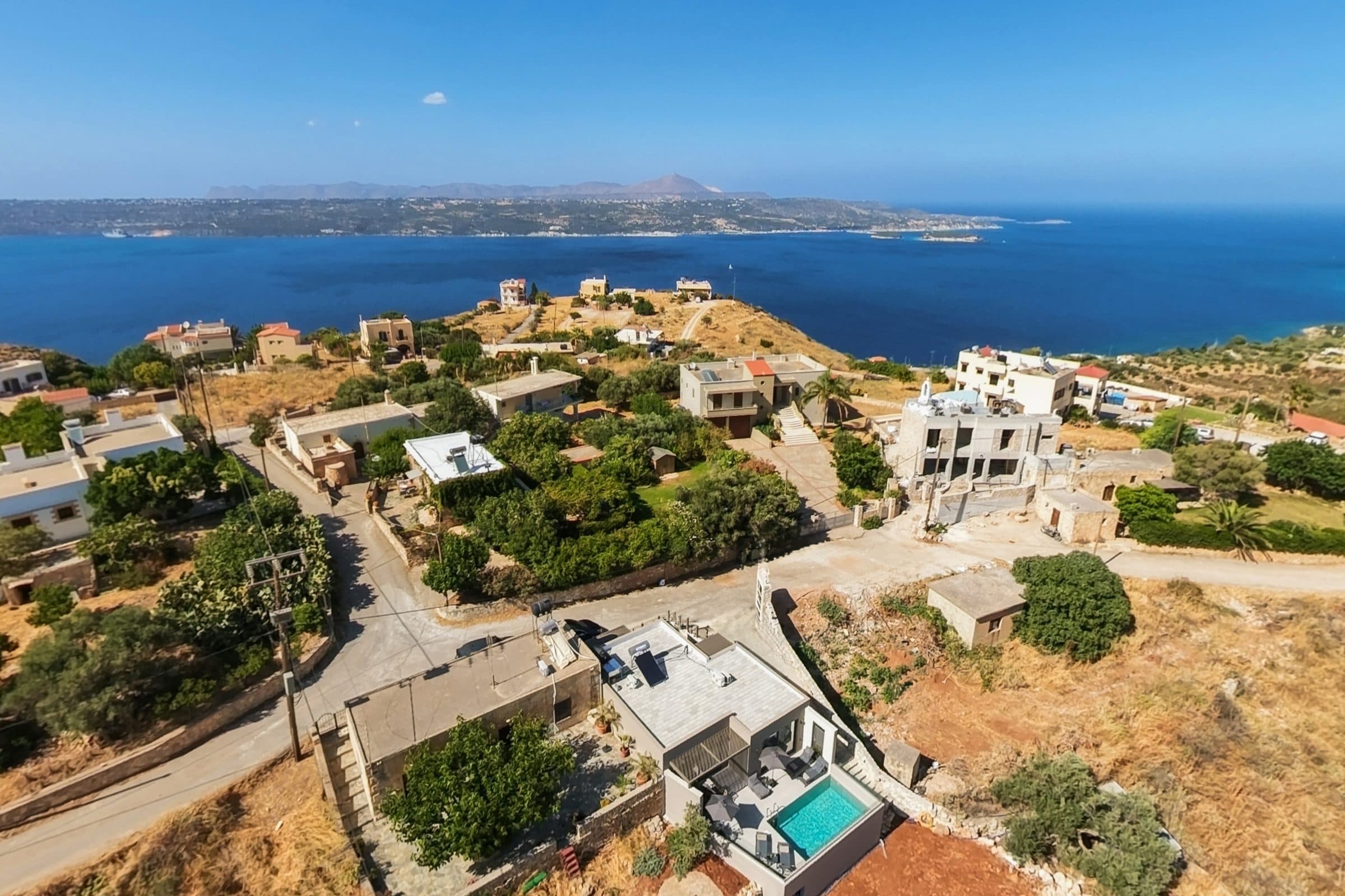 Aerial view of the village rooftops on the headland above Souda Bay, the villa and its pool in the foreground