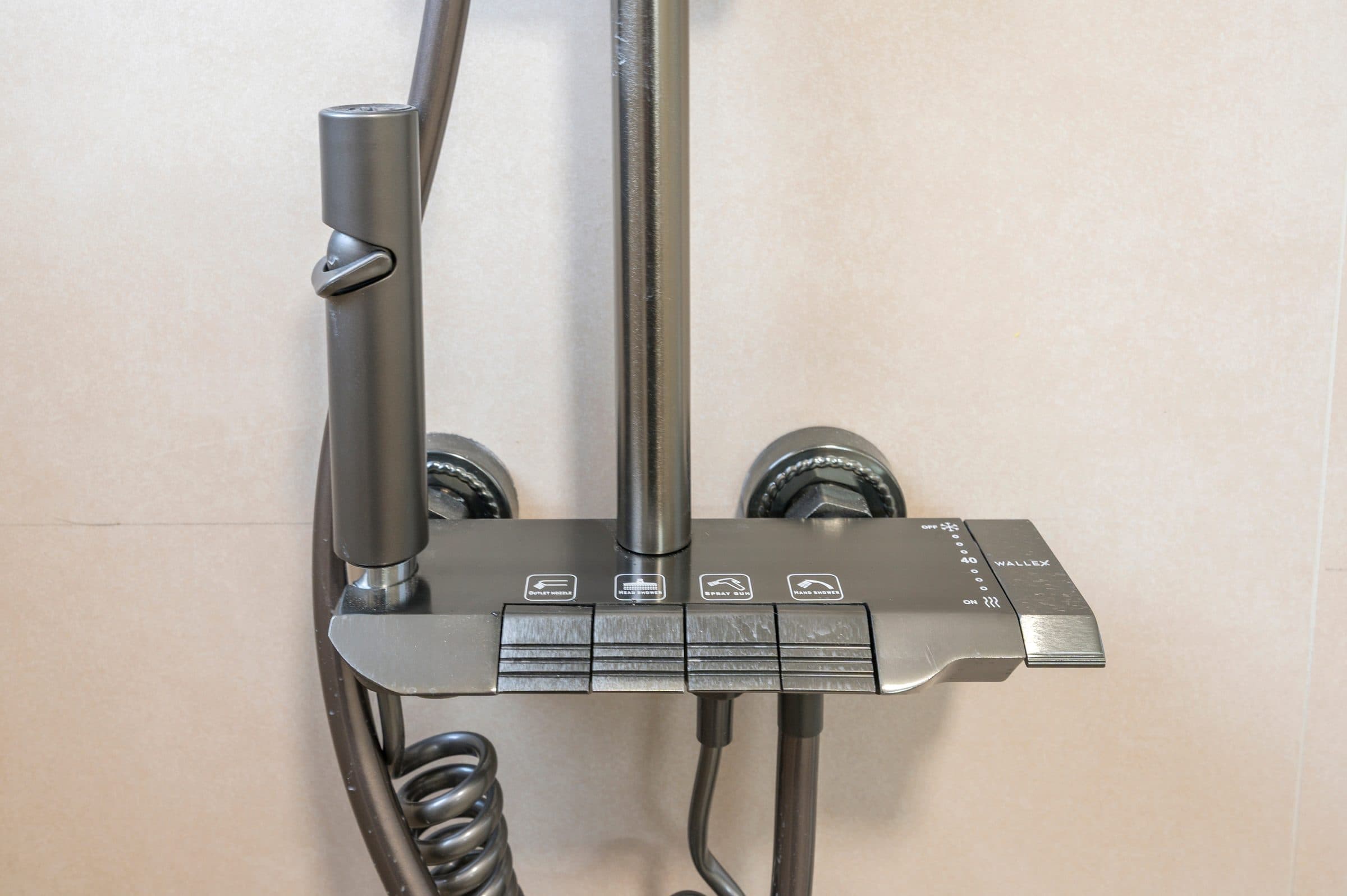 Close-up of the brushed-steel thermostatic shower column with rain head and hand shower