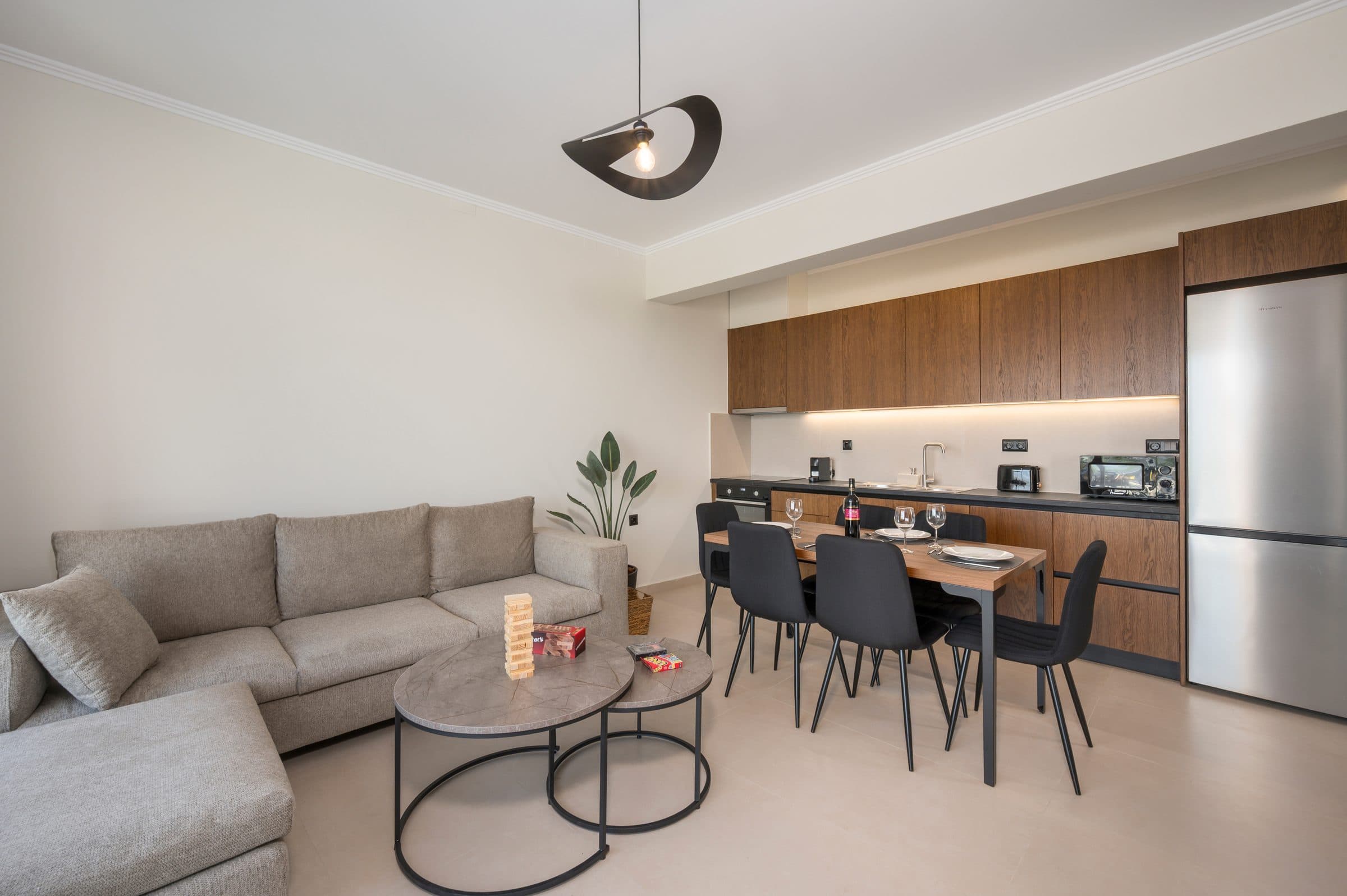 The open-plan living area: a large fabric sofa, marble nesting coffee tables and the walnut kitchen with oven, fridge and coffee machine