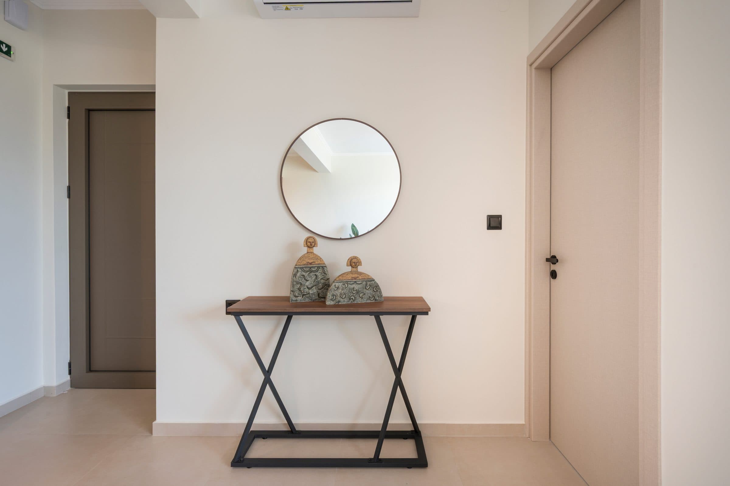 The entrance hall with a slim console table, a round mirror and two ceramic Cretan figurines