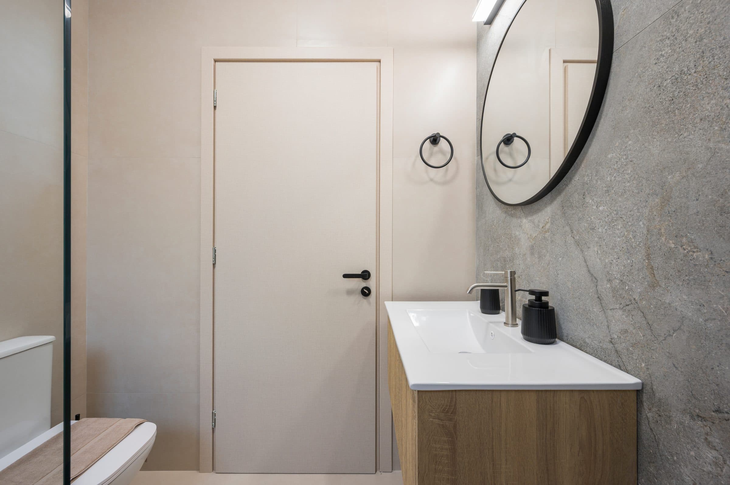 The second bathroom, with its oak vanity, round mirror and wall-hung WC beside the shower screen