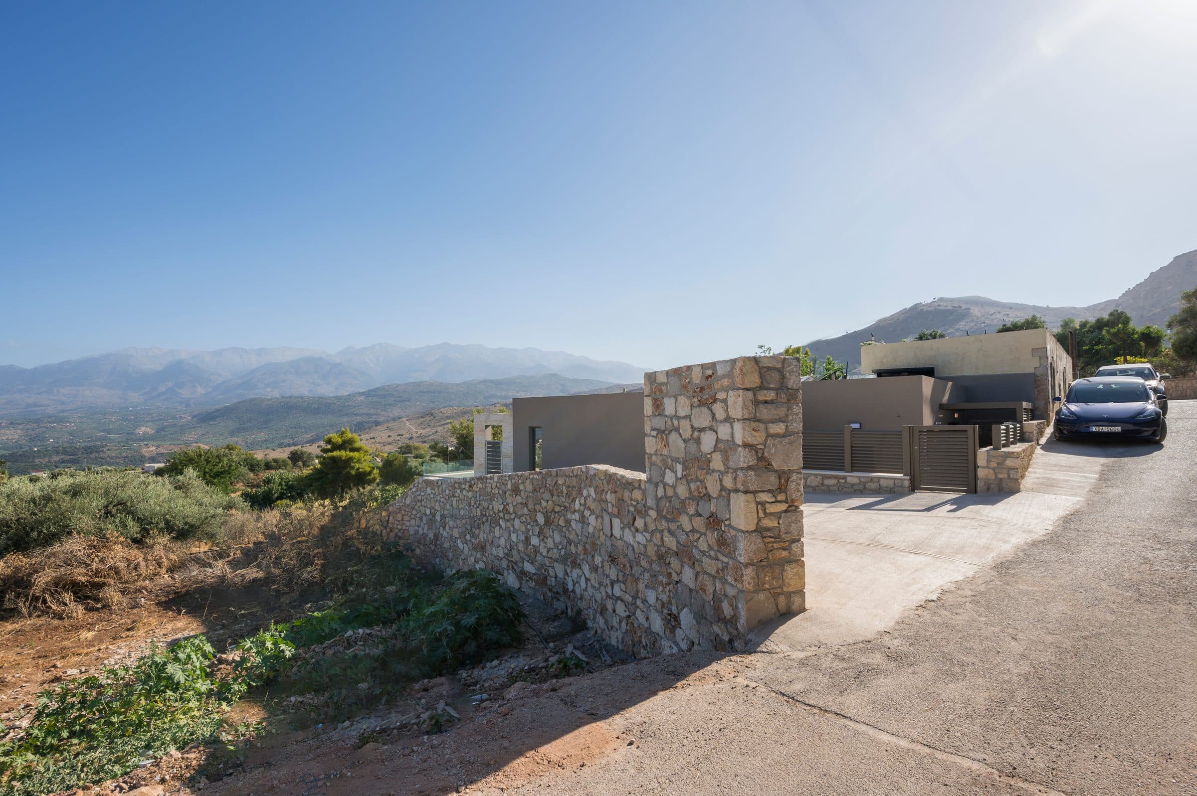 The dry-stone boundary wall and private driveway of the villa, with the White Mountains stretching across the horizon